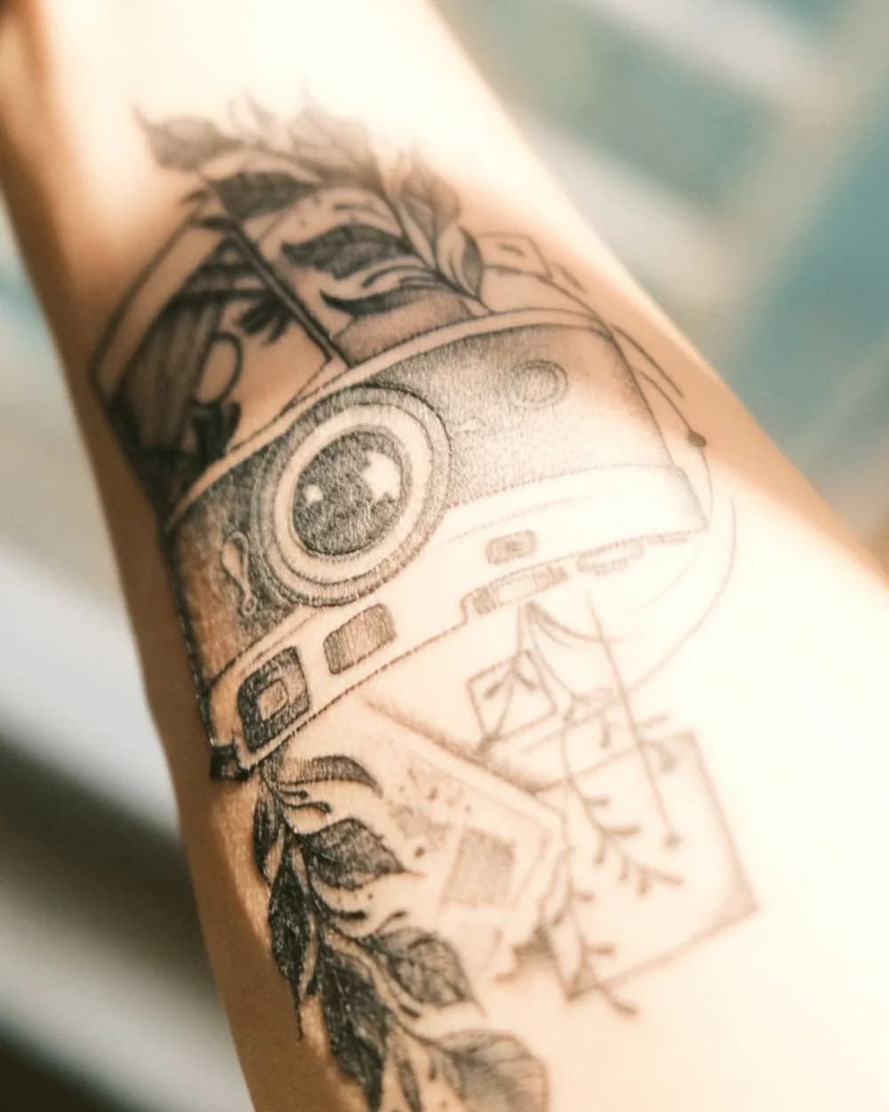 Tattoo photo taken at an angle with bright glare crossing a detailed camera and landscape design