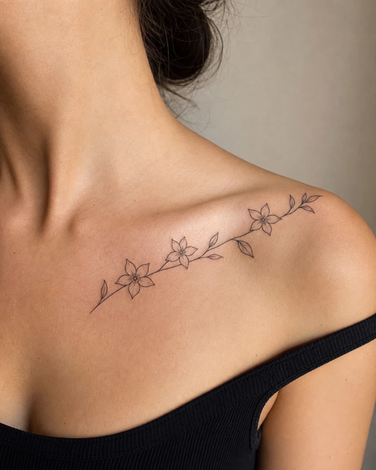 Fine line jasmine blossom arc following an adult collarbone beneath a simple neckline
